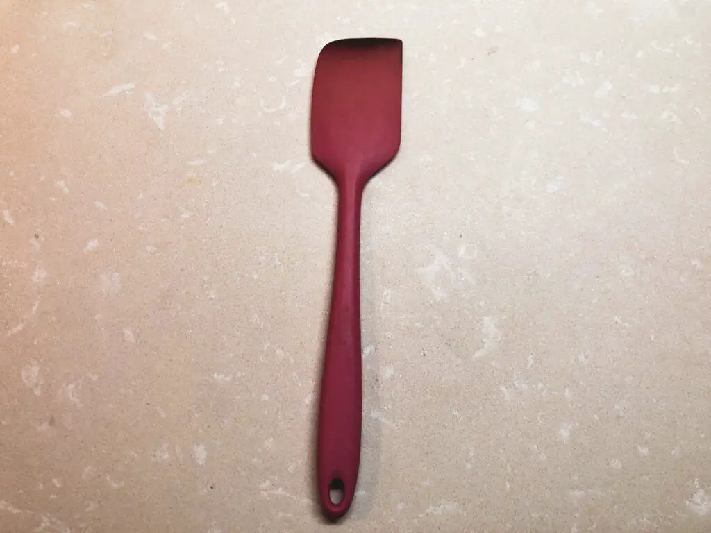A pink silicone spatula displayed on a kitchen counter top. 