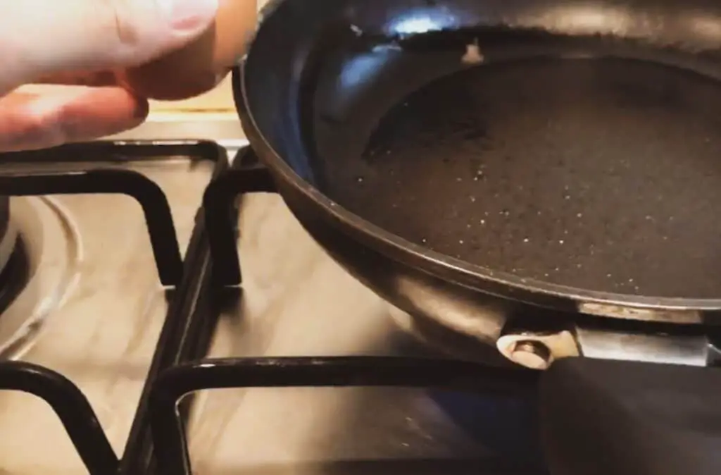 Cracking an egg into the pan.