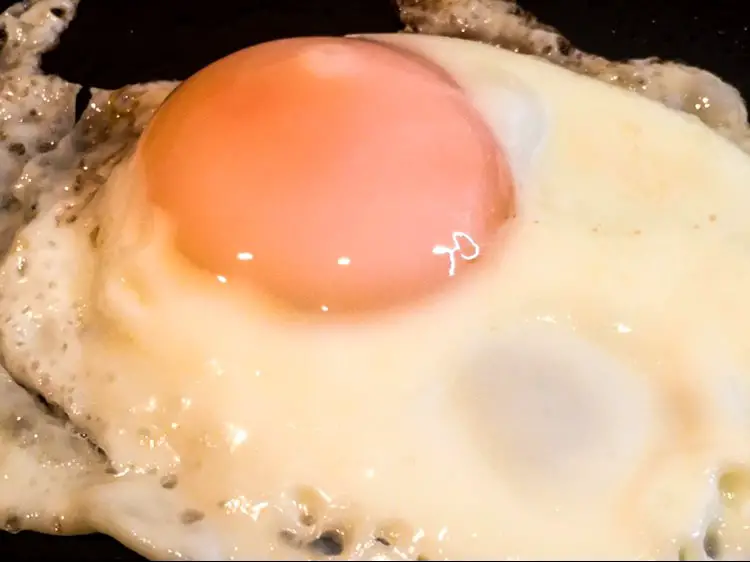 A close up of a delicious fried egg on a pan.