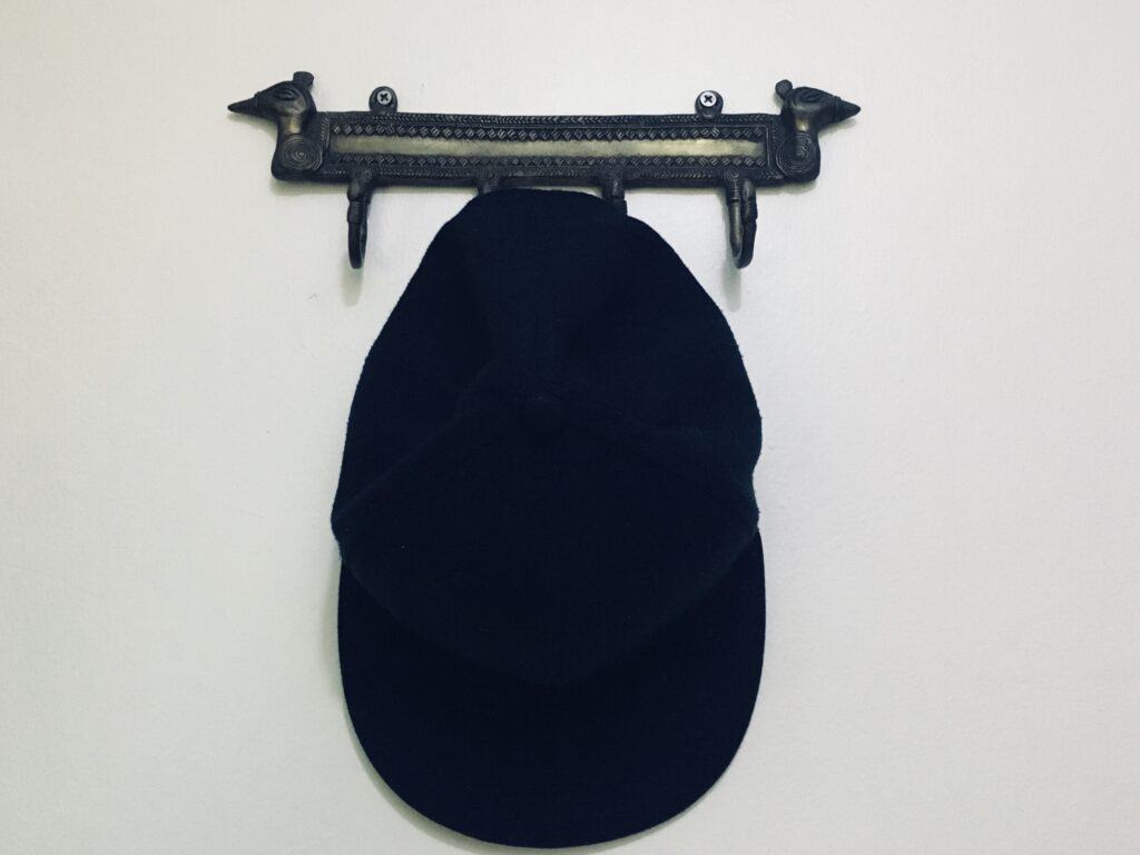 A picture of a snapback hat.cap resting/hanging on a coat rack.