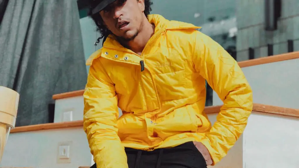 Model wearing a black hat and yellow men's bomber jacker.