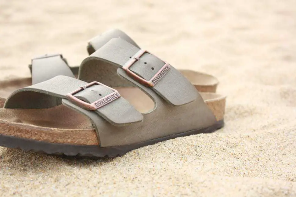 Close up of a pair of Birkenstock shoes on a bed of sand.