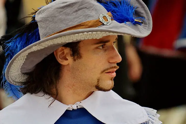 Man wearing an old style hat with a feather attached.