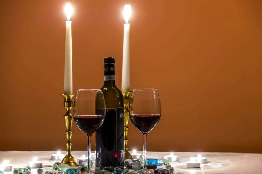 Romantic dinner table setting with candles and two glasses of wine.