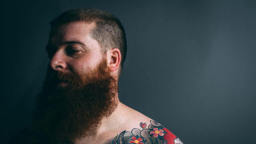 Tattooed man with burly beard and tattoos.