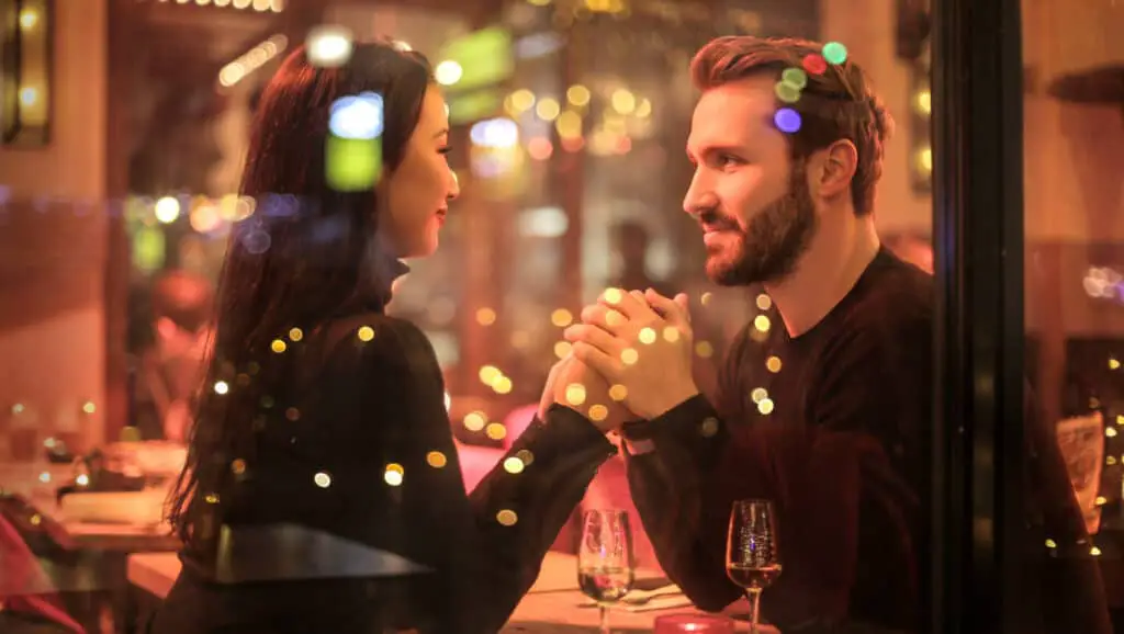 Romantic couple in restaurant holding hands over dinner.